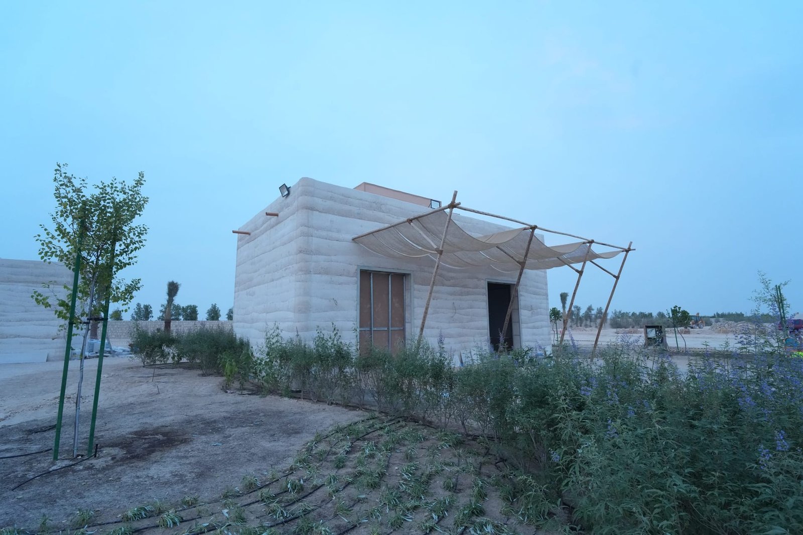 Completed in-situ rammed earth guest building with layered strata walls, Al Kaaban Resort