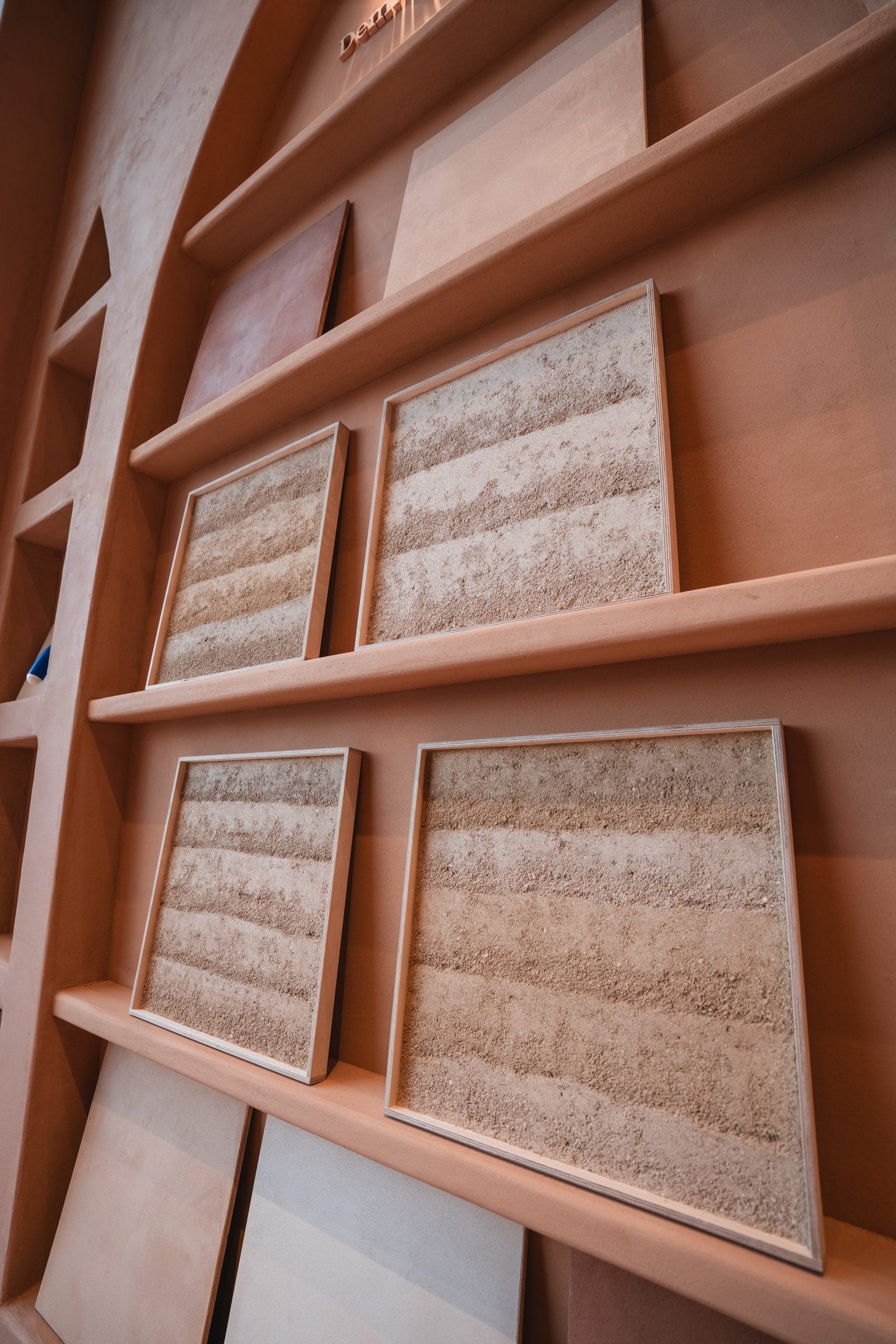 Framed Clayworks Rammed Earth Finish sample panels on plaster shelves at the Conmarble showroom in Riyadh